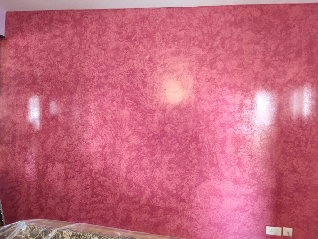 A pink wall with a large stain on it.