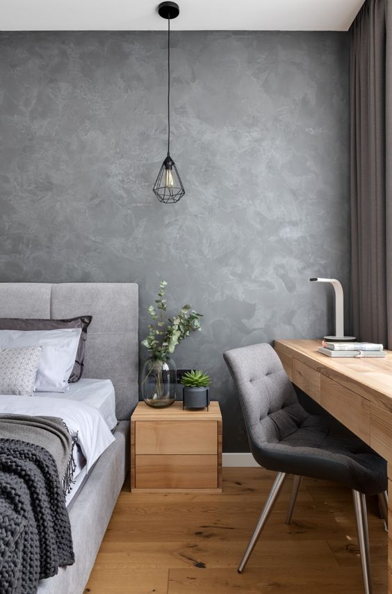 A bedroom with a grey wall and wooden floor, featuring a cozy and modern interior design.