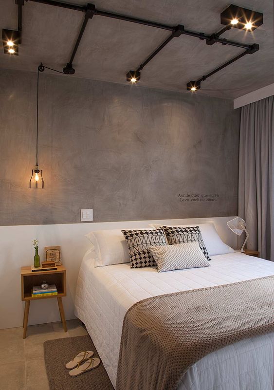 A bedroom with a white bed against a gray wall, featuring a cozy and modern design.